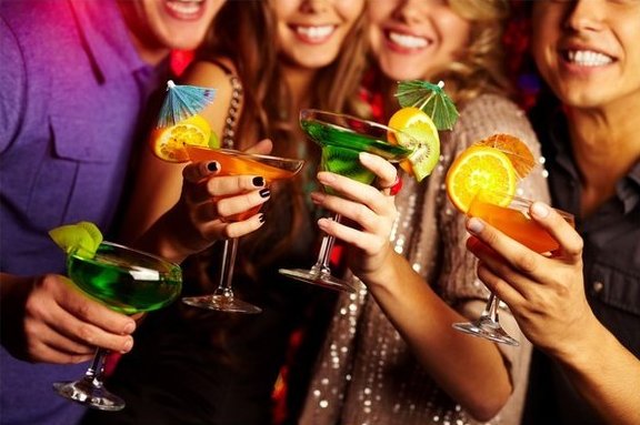 Four people holding up tropical drinks