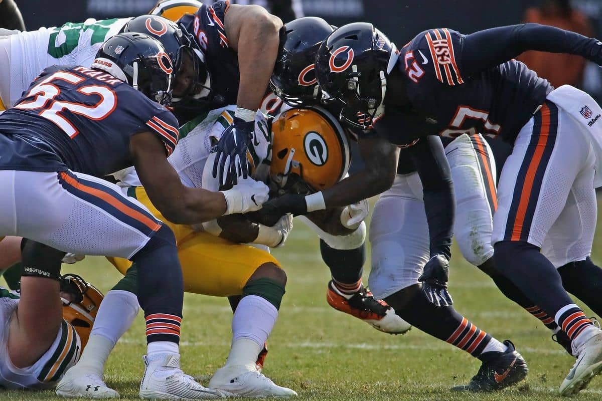 Four Chicago Bears defensive player stopping the Green Bay Packer's running back